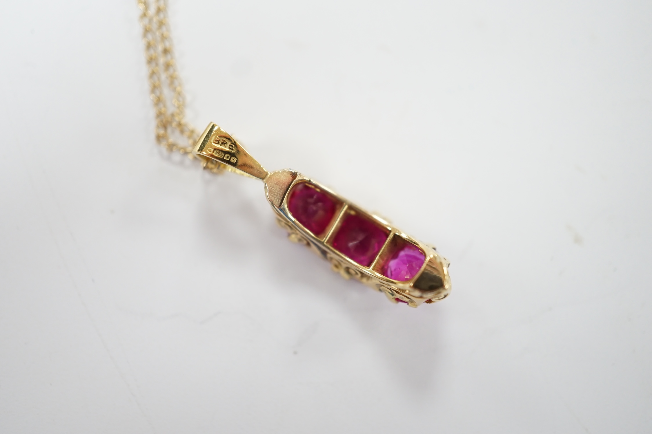 A modern 18ct gold and three stone synthetic ruby set curved pendant, with diamond chip set spacers, overall 27mm, on a 375 chain, 48cm, gross weight 4.8 grams. Condition - fair